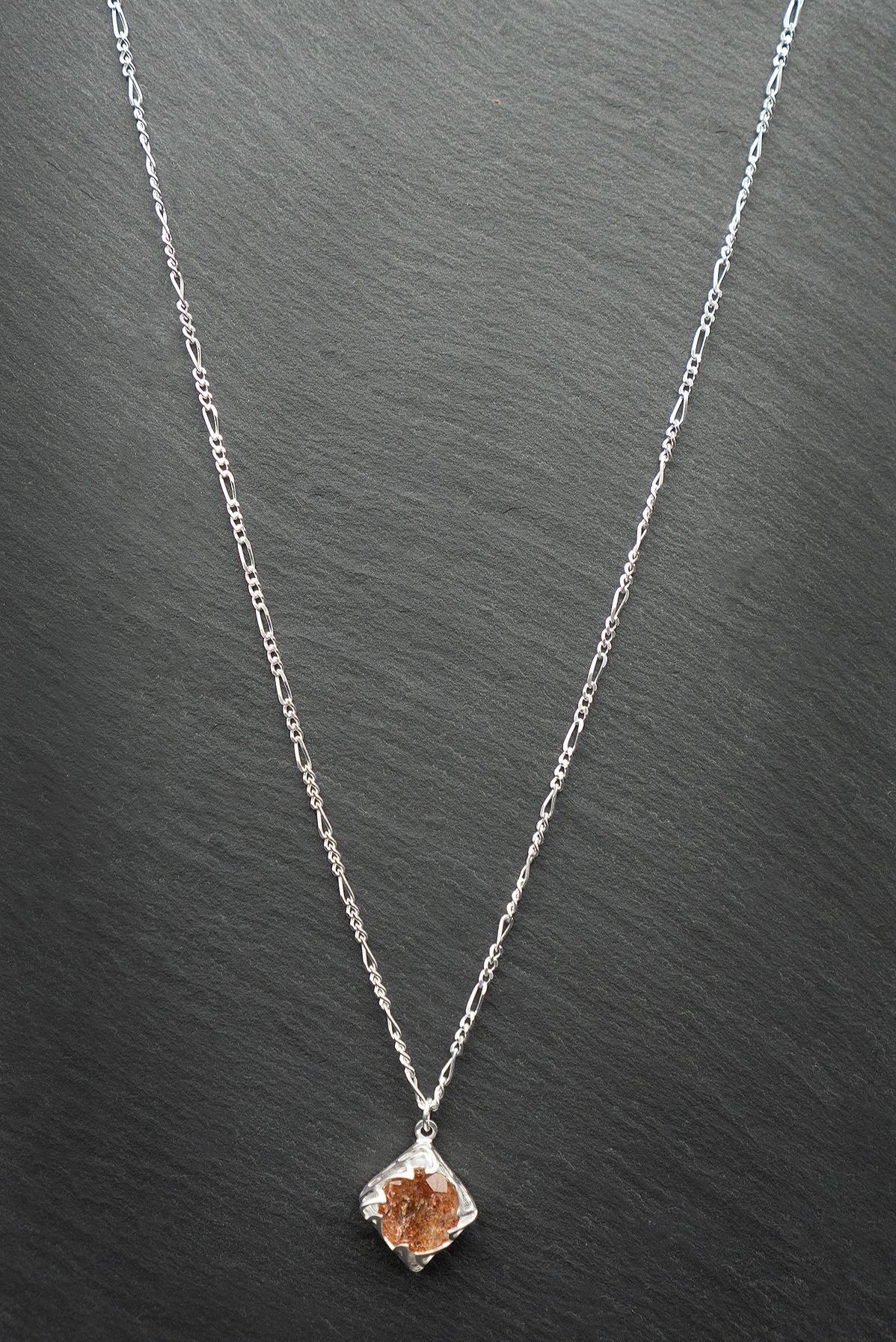 A sterling silver necklace with a faceted sunstone jewel and a diamond flame drop pendant.